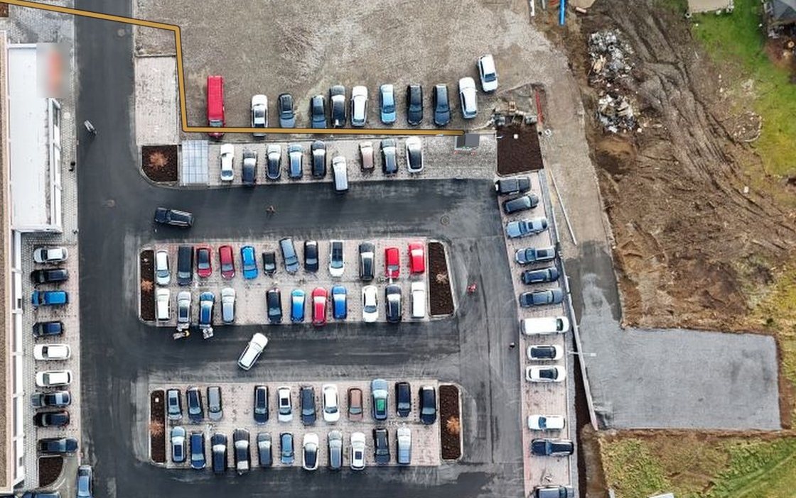 Luftaufnahme eines Parkplatzes mit eingezeichneter Kabeltrasse zwischen Gebäude und Stellplatzreihen